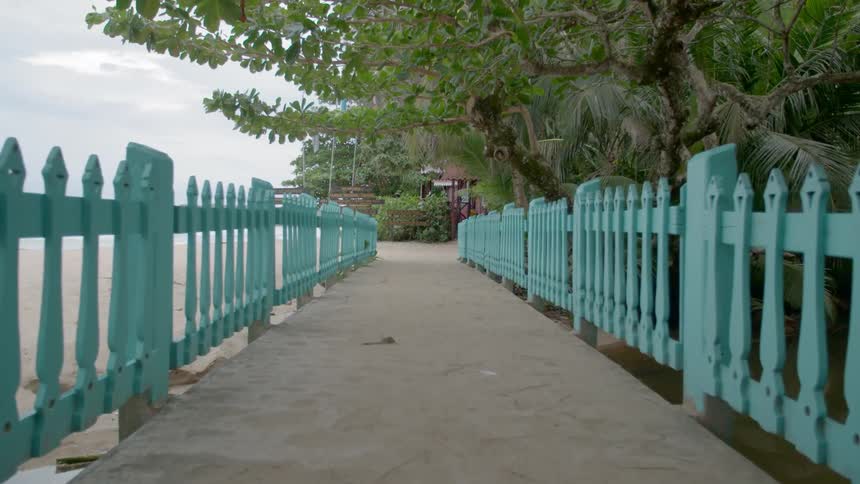 A concrete path with a fence runs along a beach