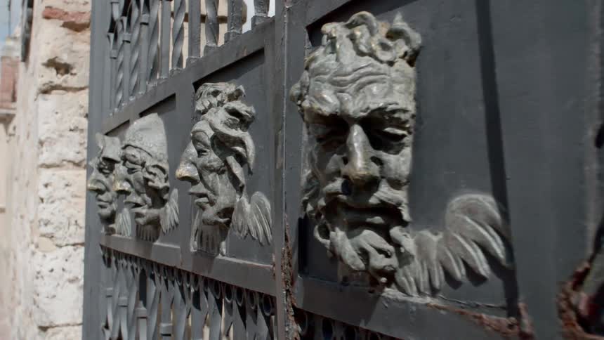 Carvings of faces on an iron gate