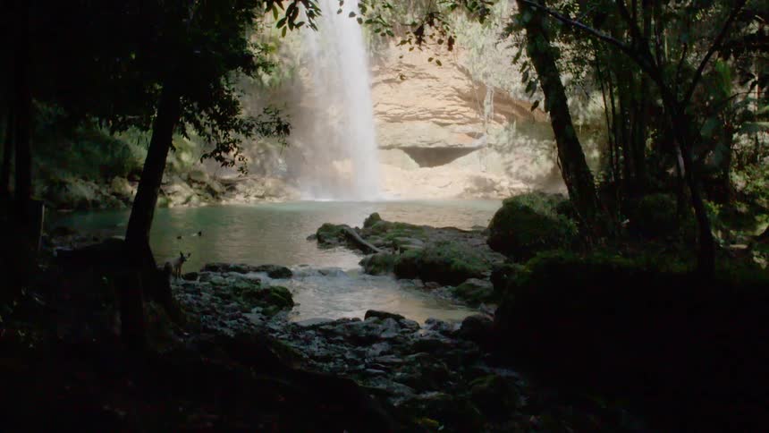 A waterfall flows into a lagoon in a tropical climate