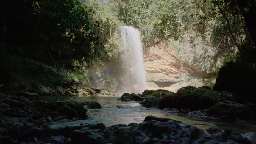 Hidden waterfall flowing in the canyon to a stream below