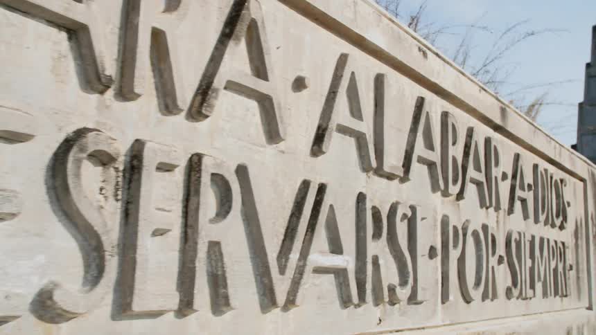 A wide stone sign with latin words on it outside a building