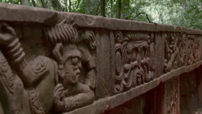 The stone carvings on a structure in a tree filled park