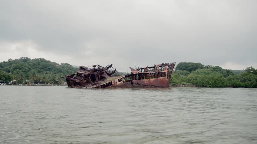 An old abandoned dilapidated boat on a river with trees in the background