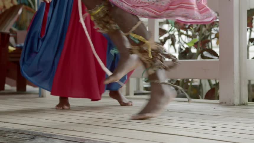 People dance on wooden flooring next to audience and railing