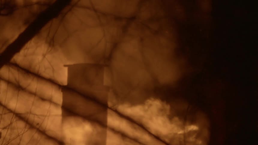 Fire engulfing a building in a wooded area