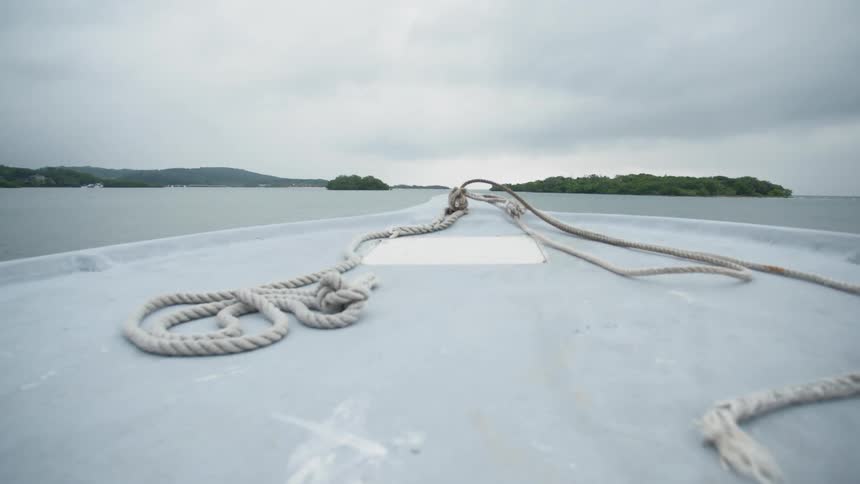Boat travels on sea towards an island on a cloudy day