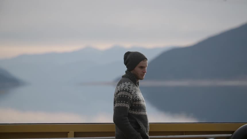 Man walking on a bridge near a lake