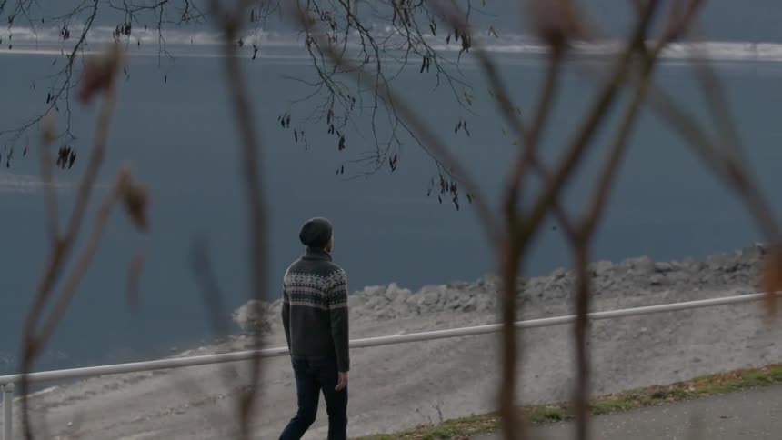 Man walks down sidewalk near a body of water