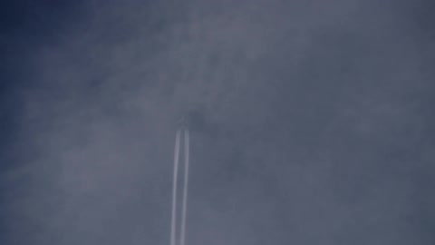 An airplane leaves a smoke trail as it flies across the sky
