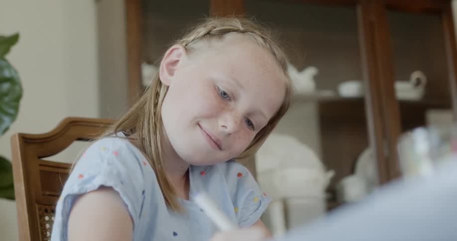 A girl sitting on a chair drawing with a marker
