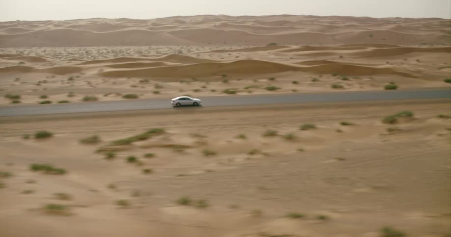 A car races down a road in the middle of a desert