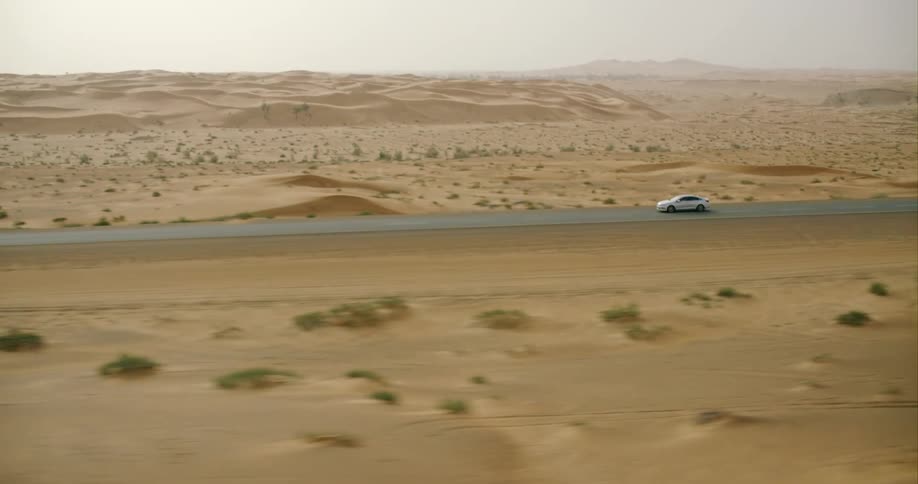 A car is driving in a desert area