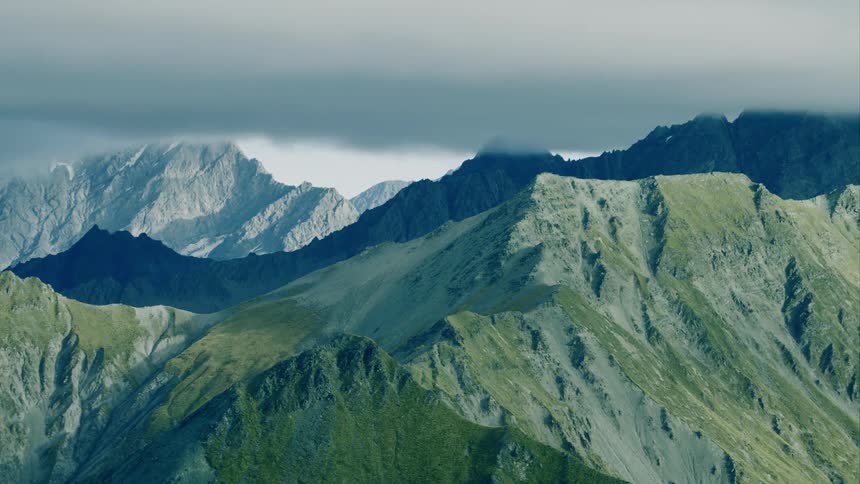 A mountain range covered with forest growth sits under dark clouds