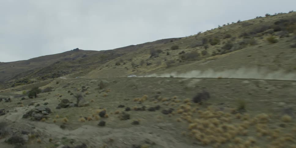 Aerial shot of sports car driving full speed on dirt road in the hills