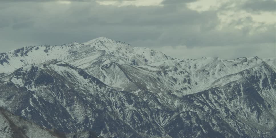 A mountain ridge covered with snow with the sky in the background
