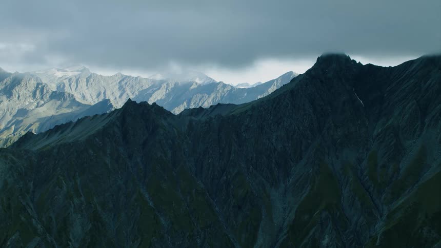 Mountains sit under dark clouds hanging down from the sky