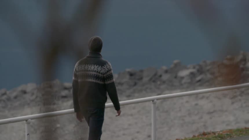 A man is walking across a railing by the beach
