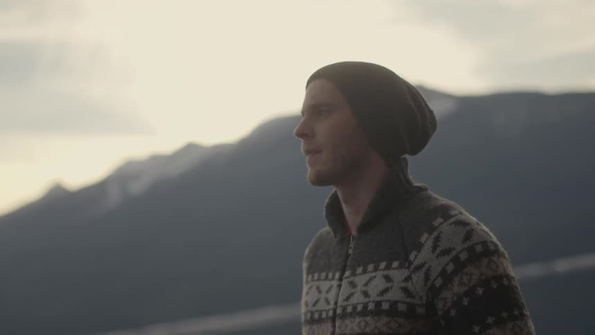 A man in a sweater looks around outside