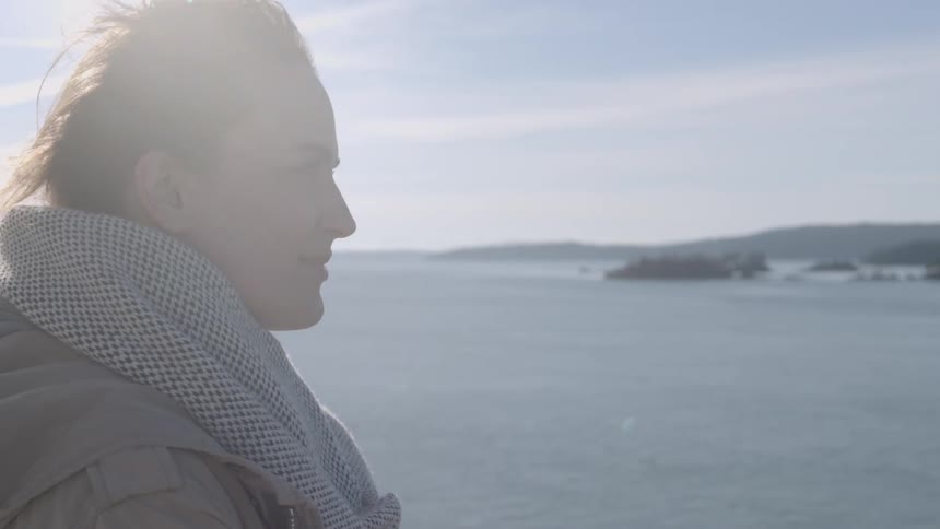 A woman standing on a beach and softly smiling