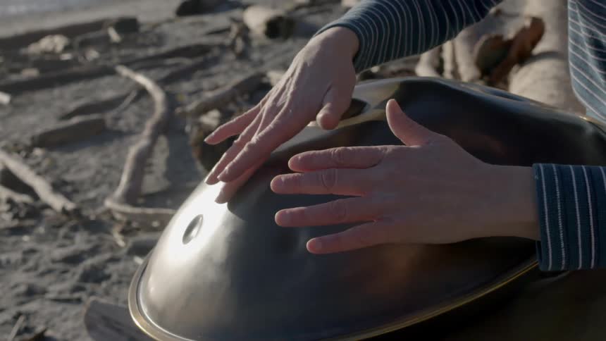 A person is playing drums by the beach