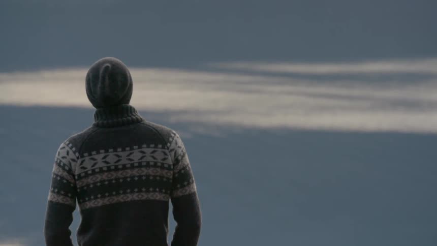 A man in a beanie looks around