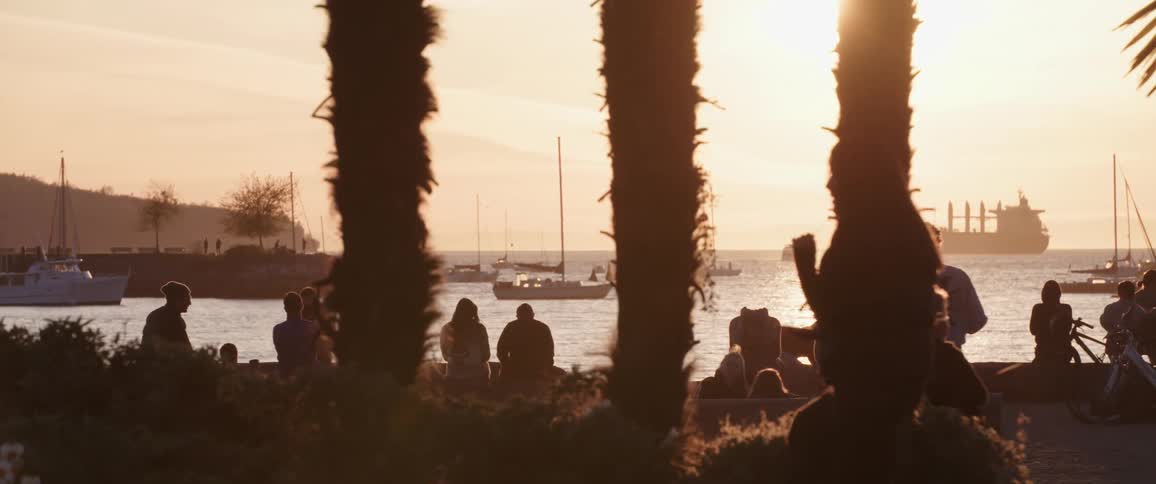 People relaxing at pier next to the ocean at sunset