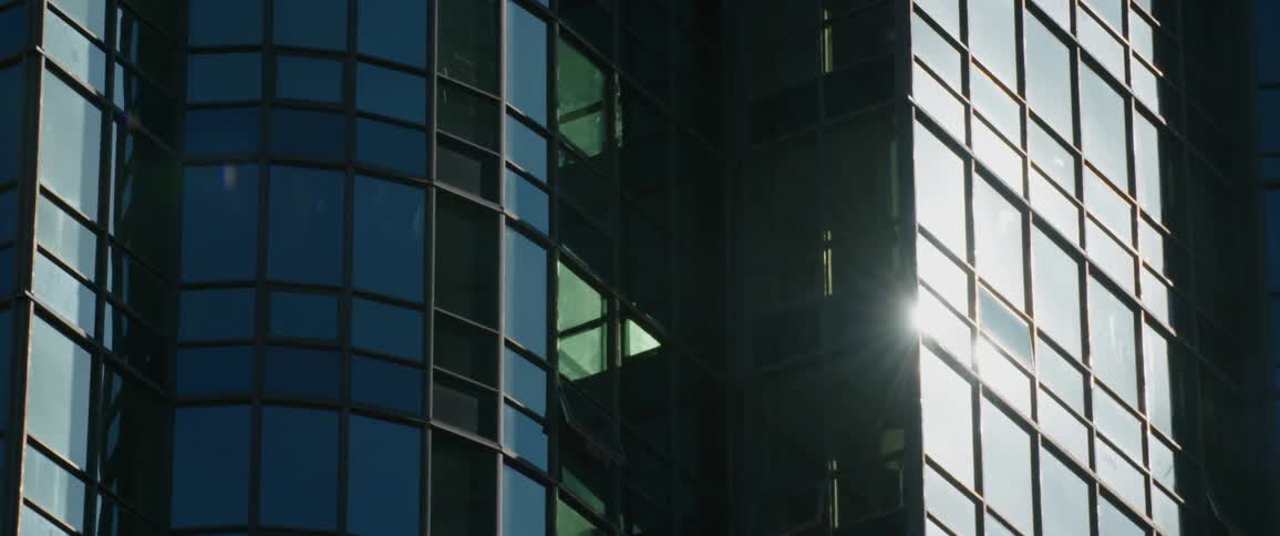Sunlight reflects off the glass windows of a high rise building