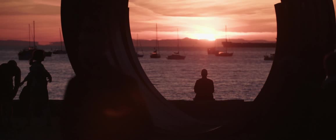 People relaxing on a pier next to the ocean at sunset