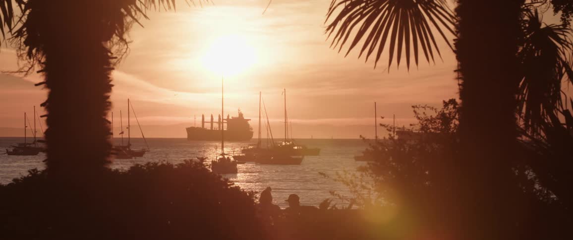People relaxing at pier next to the ocean at sunset