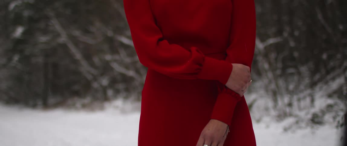 The woman stands near the trees