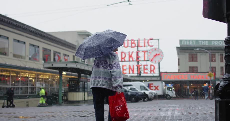 An older lady is holding an umbrella in a Seattle snow storm