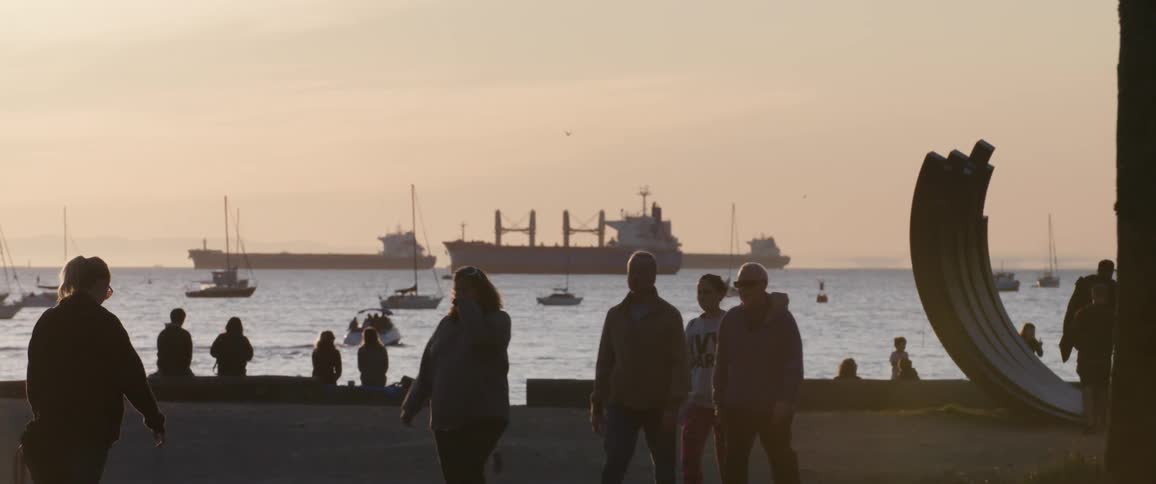 Boats in the water while people and cyclists are on the shore