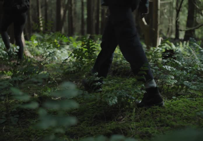 A man and a woman hike through a thick forest