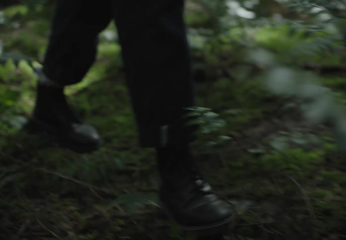 A man and a woman walk through a forest