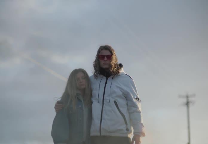 Young couple stands in front of a fire at sunset