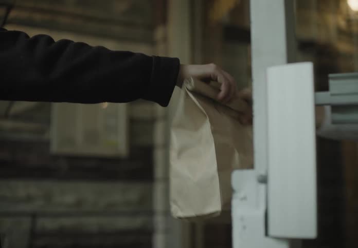 The person hands the brown bag over
