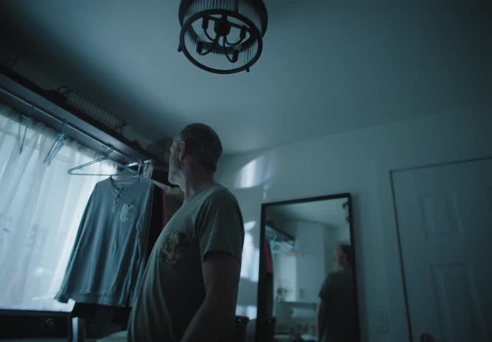 Man stands and looks out the window in a dim lit room
