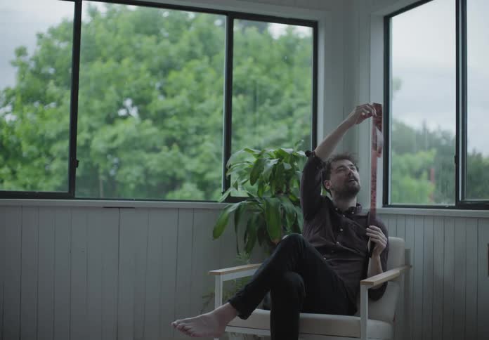 Man sitting in a chair in corner of room looking at a film strip