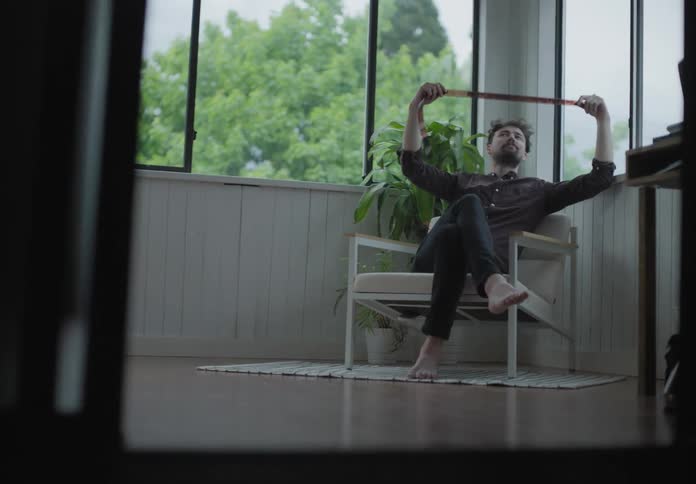 Bearded man sits on chair in the porch checking film negatives