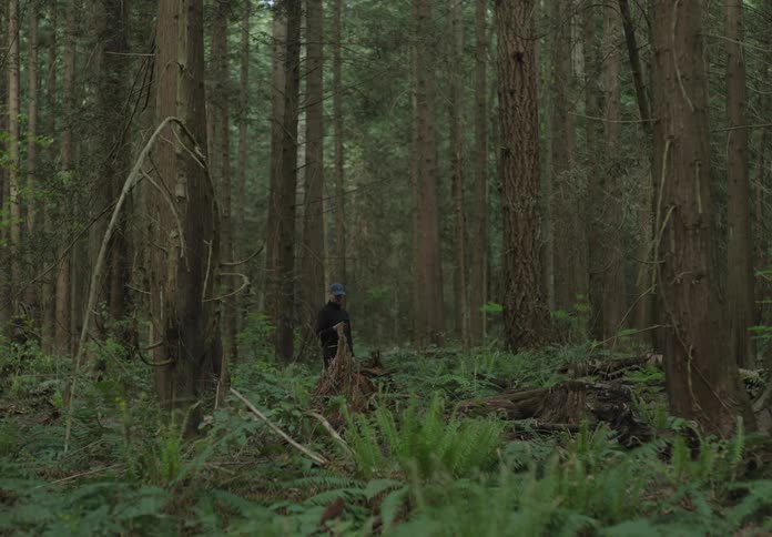 A white man runs through a thick forest