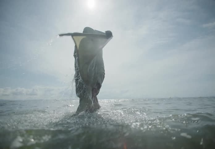 A person with a sheet over their head stands up in a lake