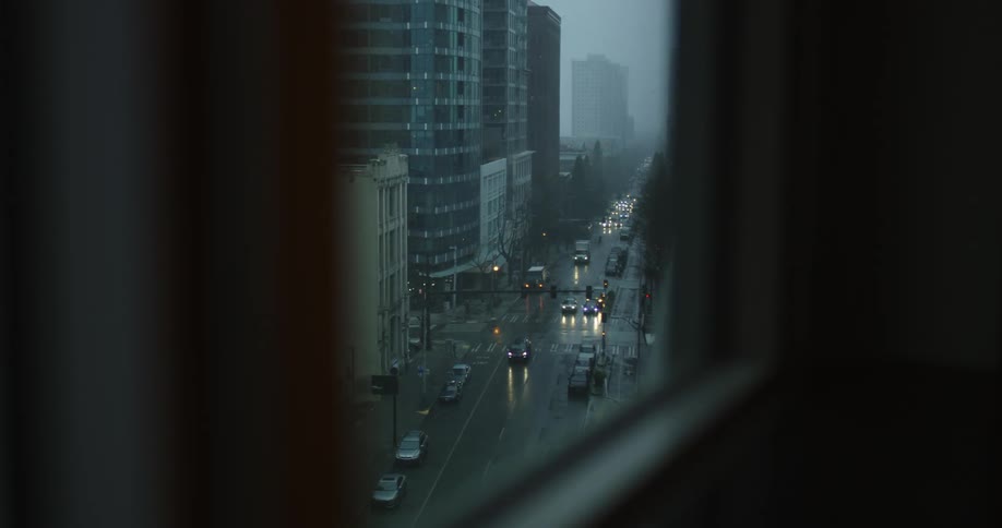 A window that shows a city street with vehicles and buildings