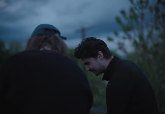 Two white men stand outdoors and talk
