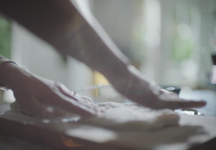 A white woman kneads dough on a wood block in a kitchen