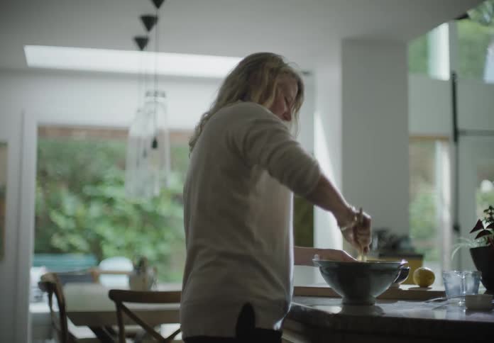 Woman stands at counter mixing dough in bowl