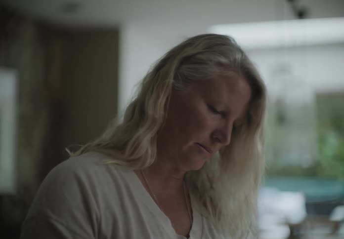 A white woman stands in a room and takes a deep breath
