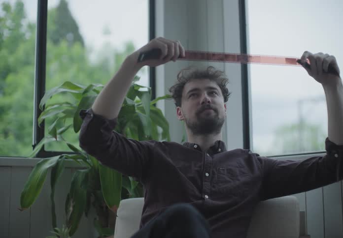 A man sitting in a chair analysing film reel