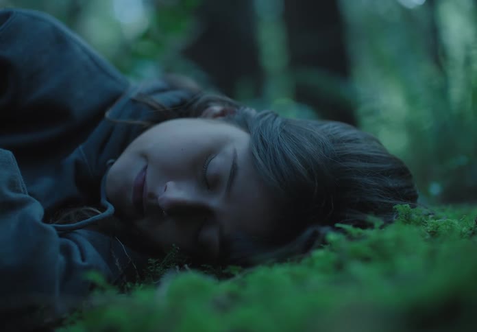 A woman is sleeping outdoors in a nature area