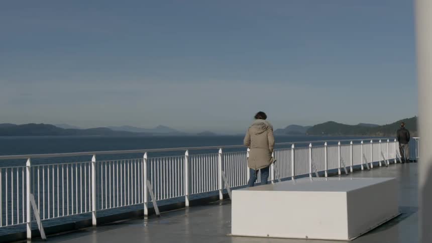 A woman wearing a heavy coat walks on a pier during the day