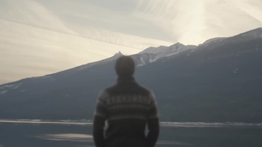 A man looking out over a mountain lake